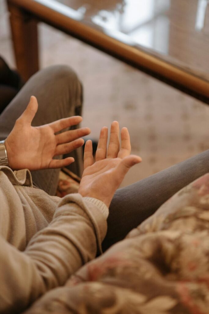 Close-up of hands gesturing in casual indoor setting, highlighting communication.